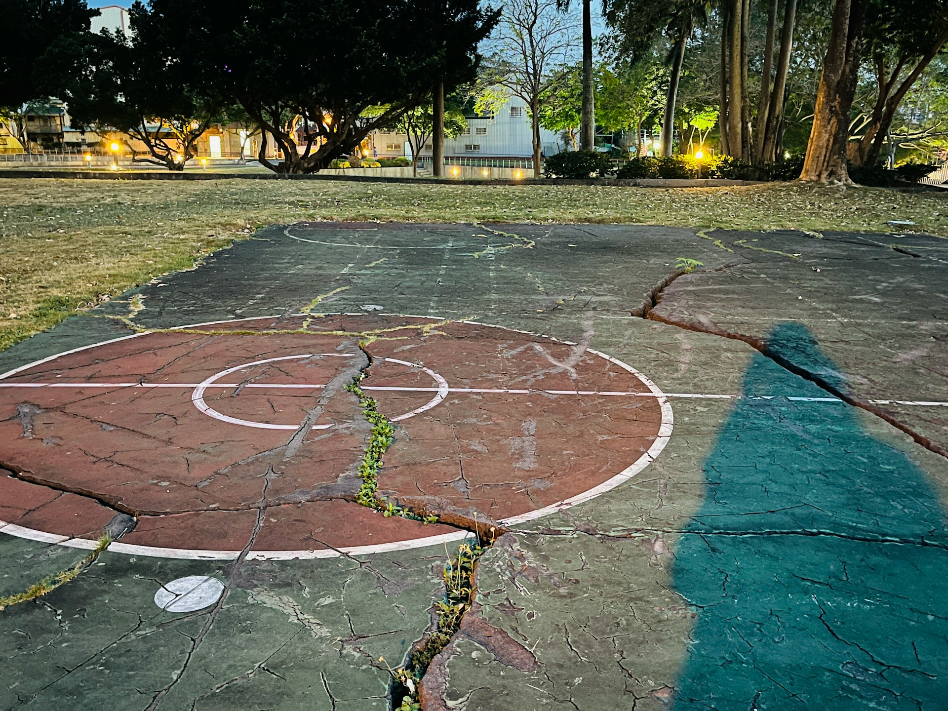 Cracked basketball court with with trees in the background