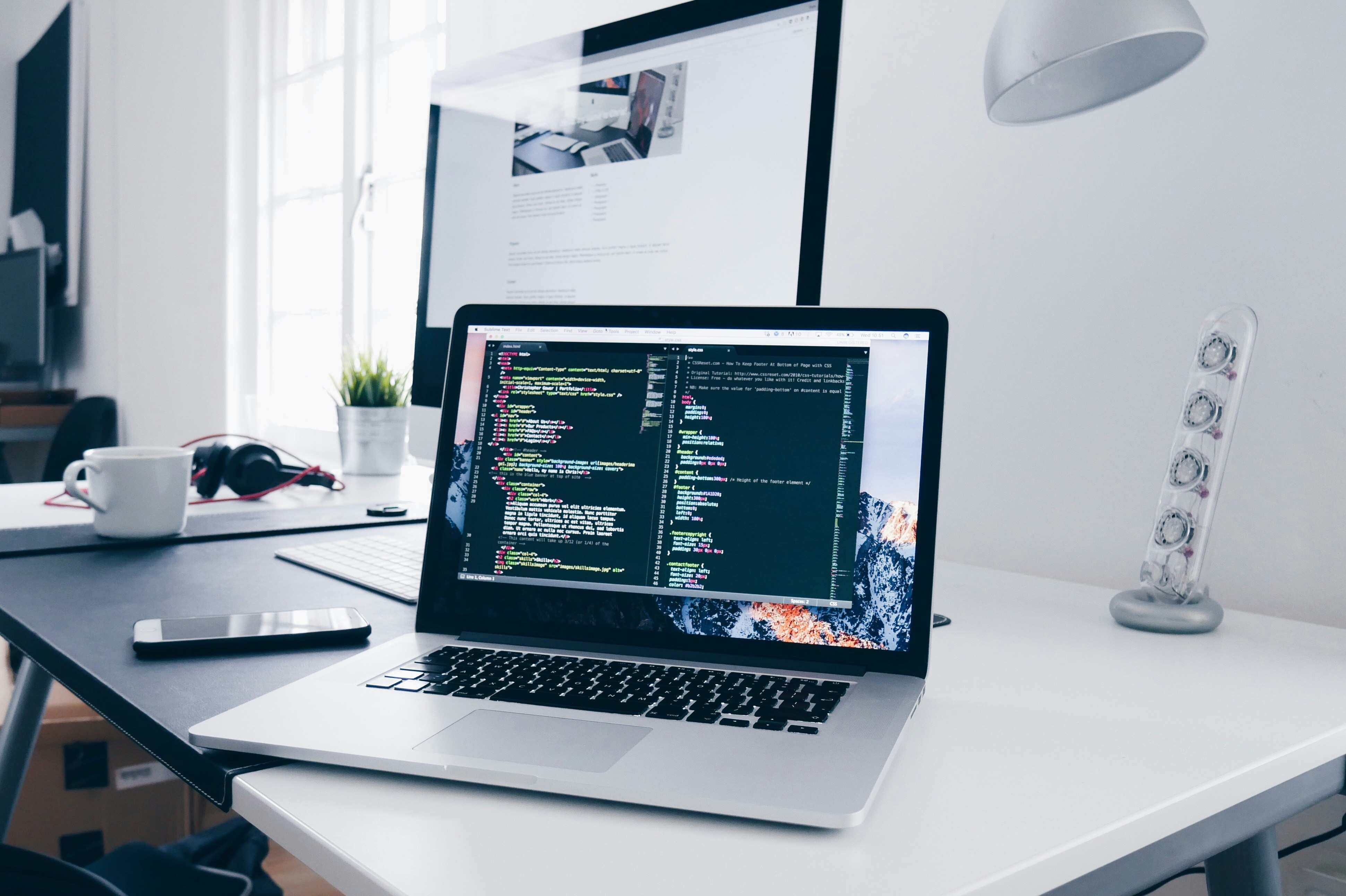 Laptop displaying software code on desk